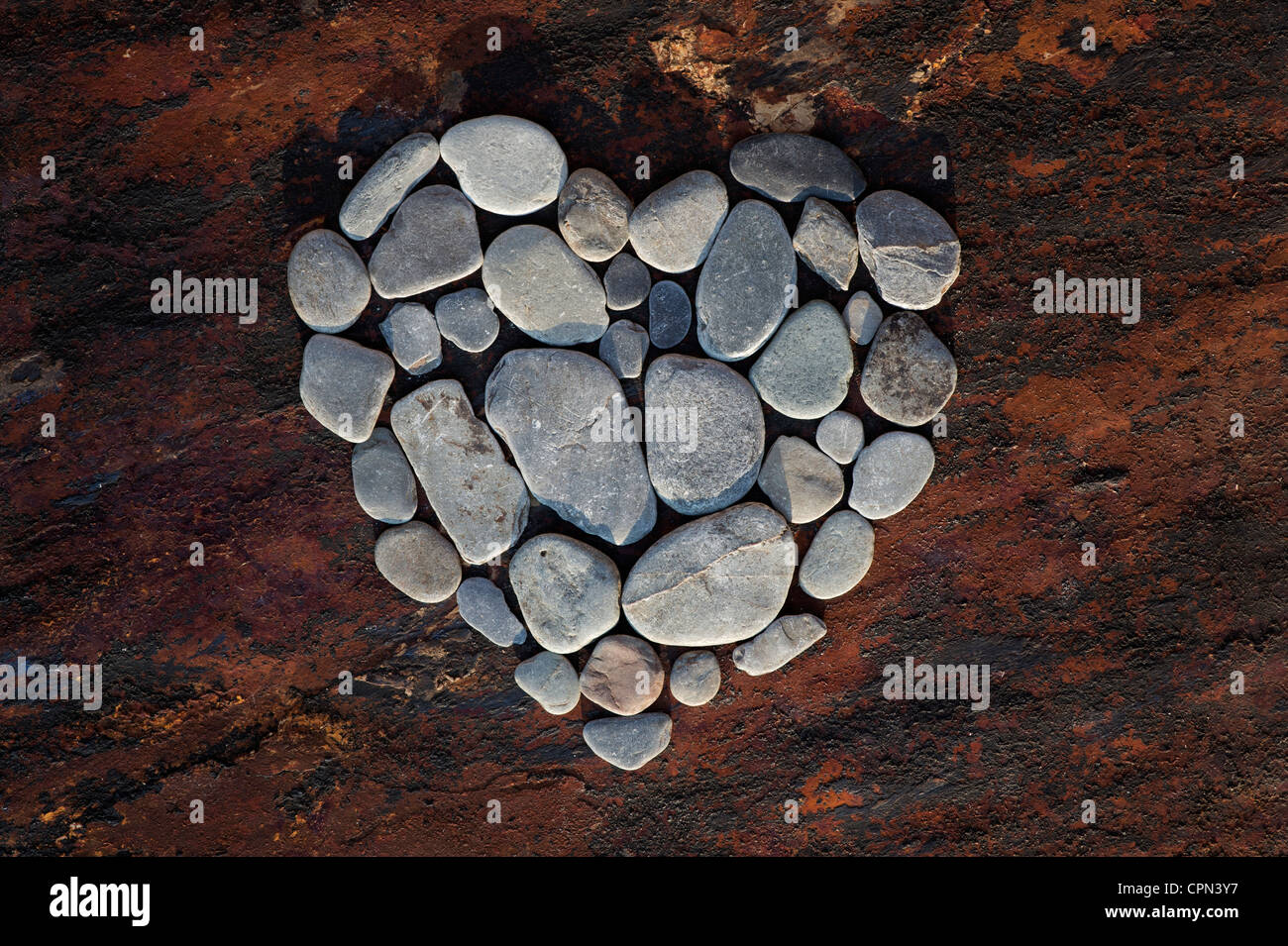 Forme de coeur galets sur une texture de fond d'ardoise Banque D'Images