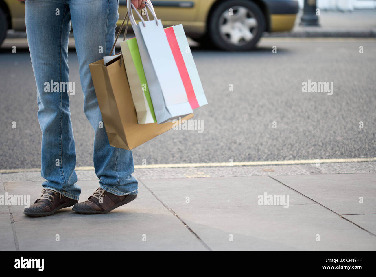 Shopper carrying shopping bags, low section Banque D'Images