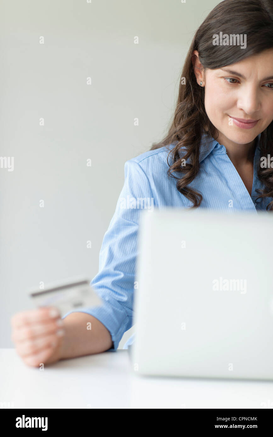 Mid-adult woman holding credit card while using laptop computer Banque D'Images