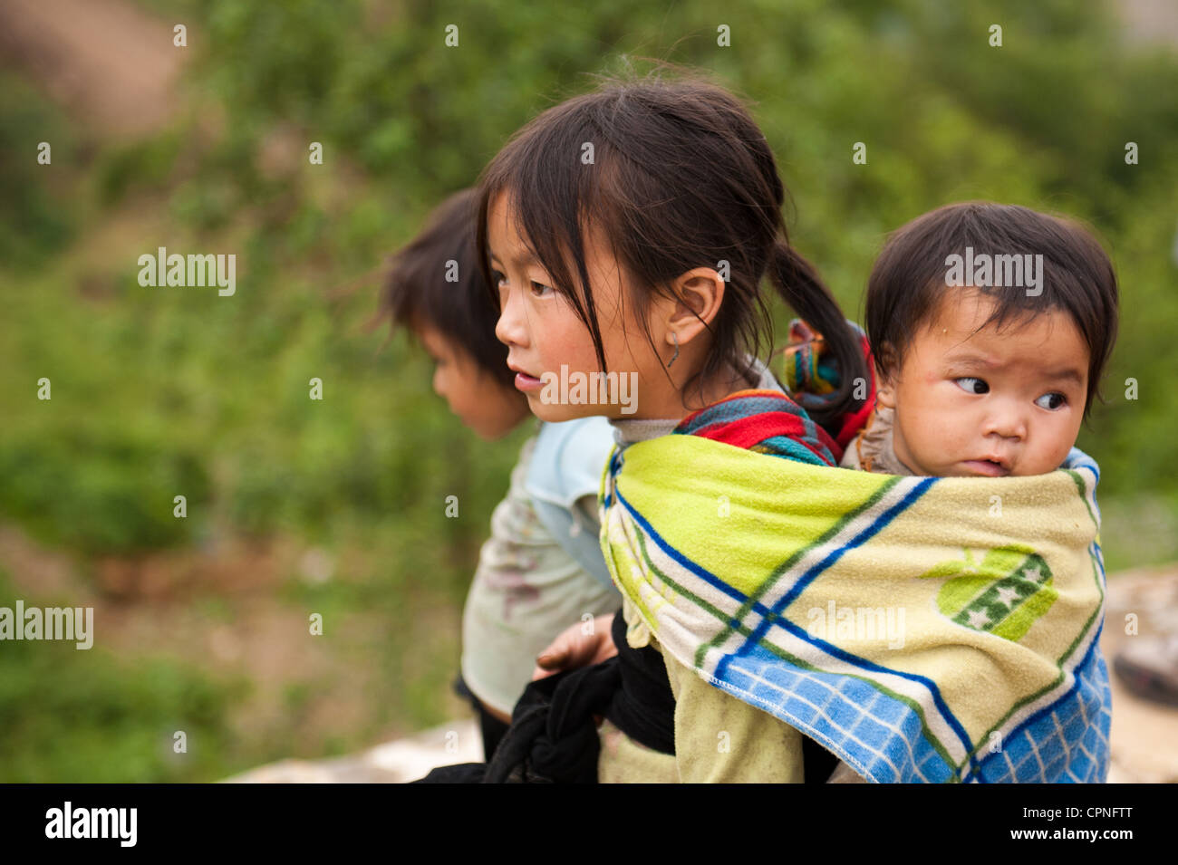 H'Mong girl carrying baby sister Banque D'Images