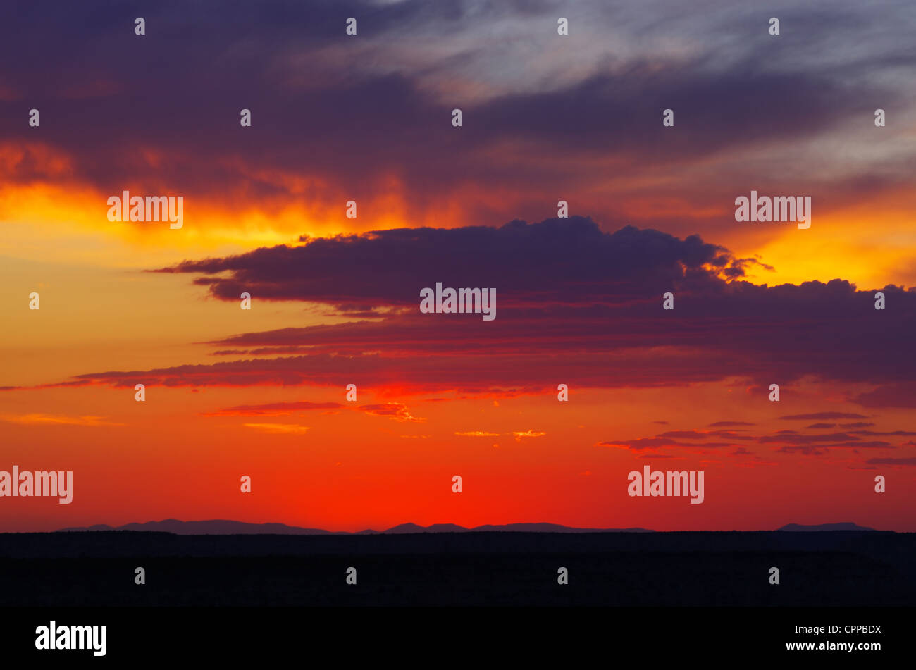Coucher de soleil depuis le Grand Canyon avec des montagnes au loin et les nuages rouges et orange Banque D'Images