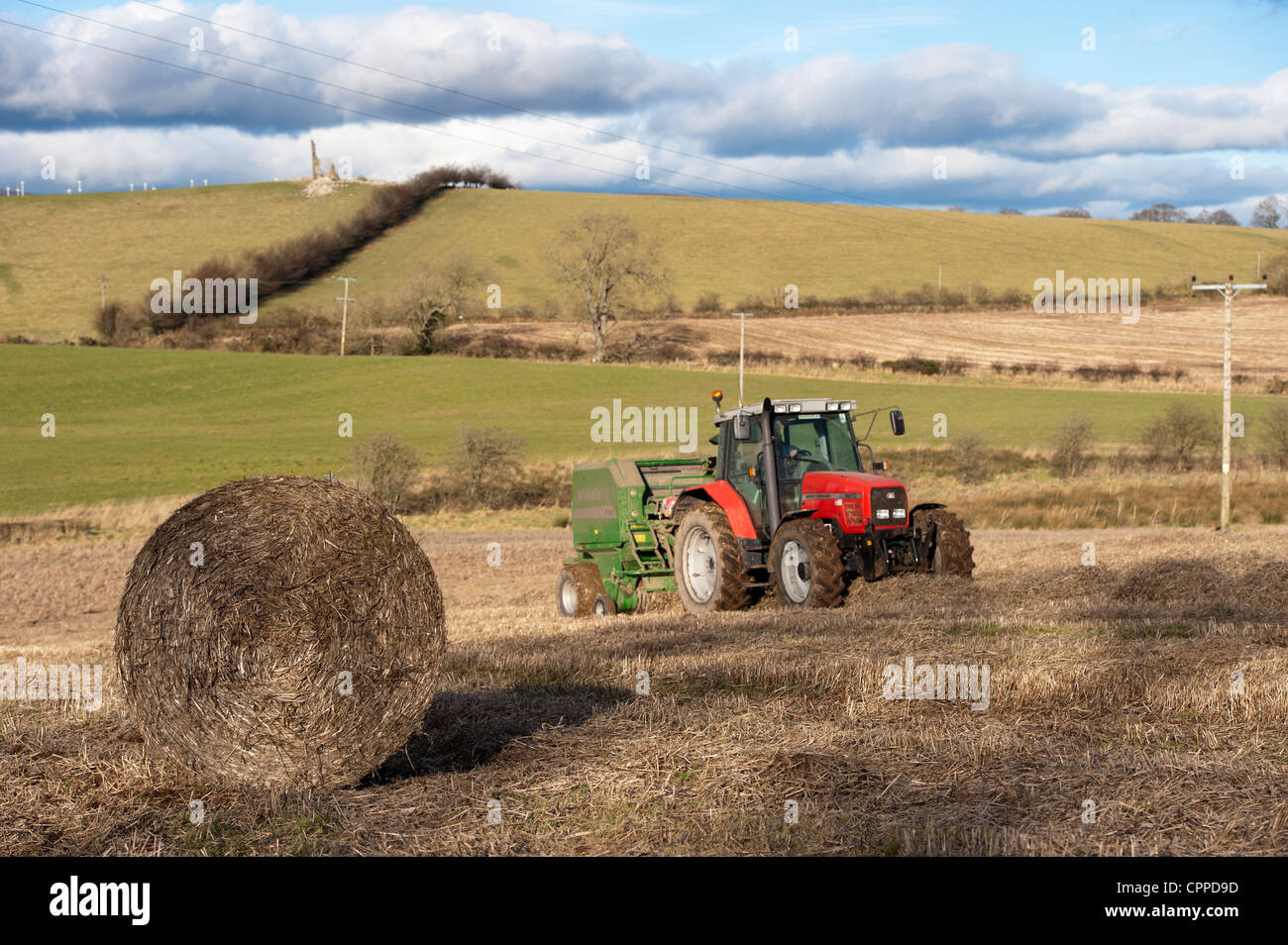 La mise en balles de paille avec McHale et balles rondes tracteur Massey Ferguson. Banque D'Images