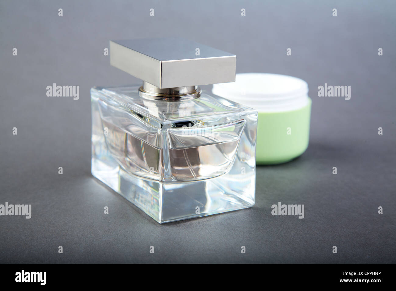 Flacon de parfum et le tube d'une crème cosmétique sur fond gris Banque D'Images