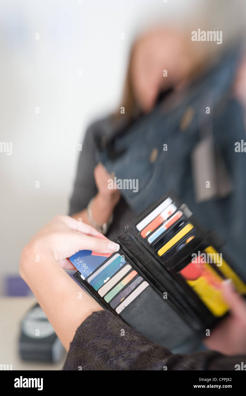 Woman's hand retrait de carte de crédit un sac à main en arrière plan commander 24 et shop assistant portant la mention jeans Banque D'Images