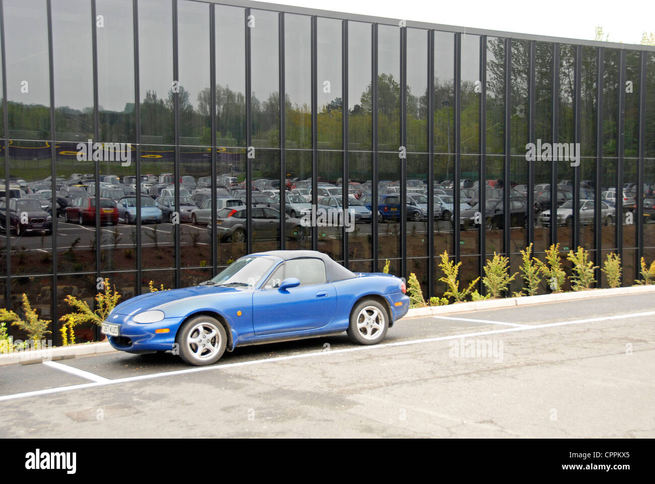 Voitures dans parking reflète dans de grandes fenêtre verre Banque D'Images