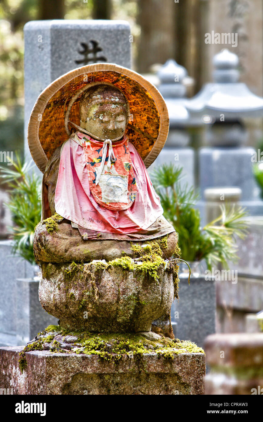 Une statue bouddhiste de Jizo-bosatsu, feuille de lotus en pierre japonaise, portant un bavoir rouge et un chapeau de paille conique dans le célèbre ancien cimetière d'Okunoin à Koya au Japon. Banque D'Images