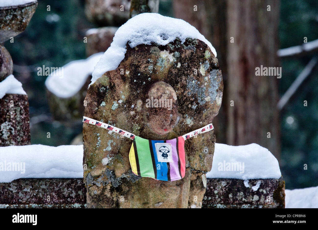 Le Japon, Koyasan, Okunoin cemetery. La neige ancienne woren Jizo de pierre-bosatsu statue bouddhiste sur pierre. bibbed. L'hiver Banque D'Images