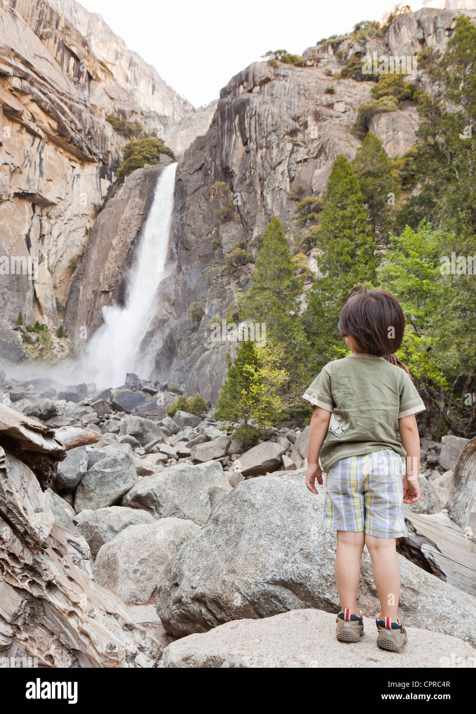 Un petit garçon debout sur des rochers, près d'une chute Banque D'Images