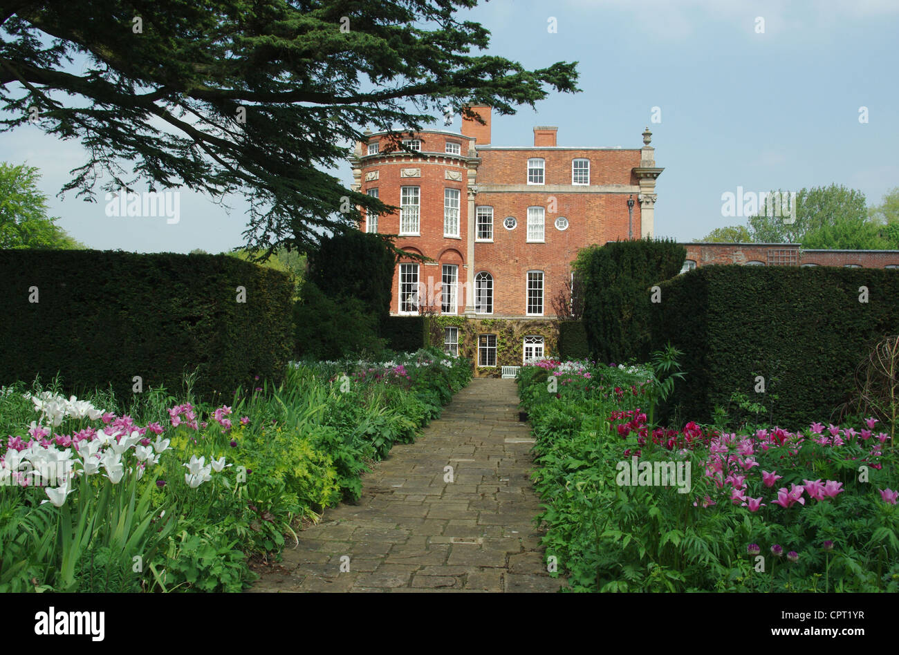 Une vue de Cottesbrooke Hall, le Northamptonshire, avec des fleurs colorées dans l'avant-plan Banque D'Images