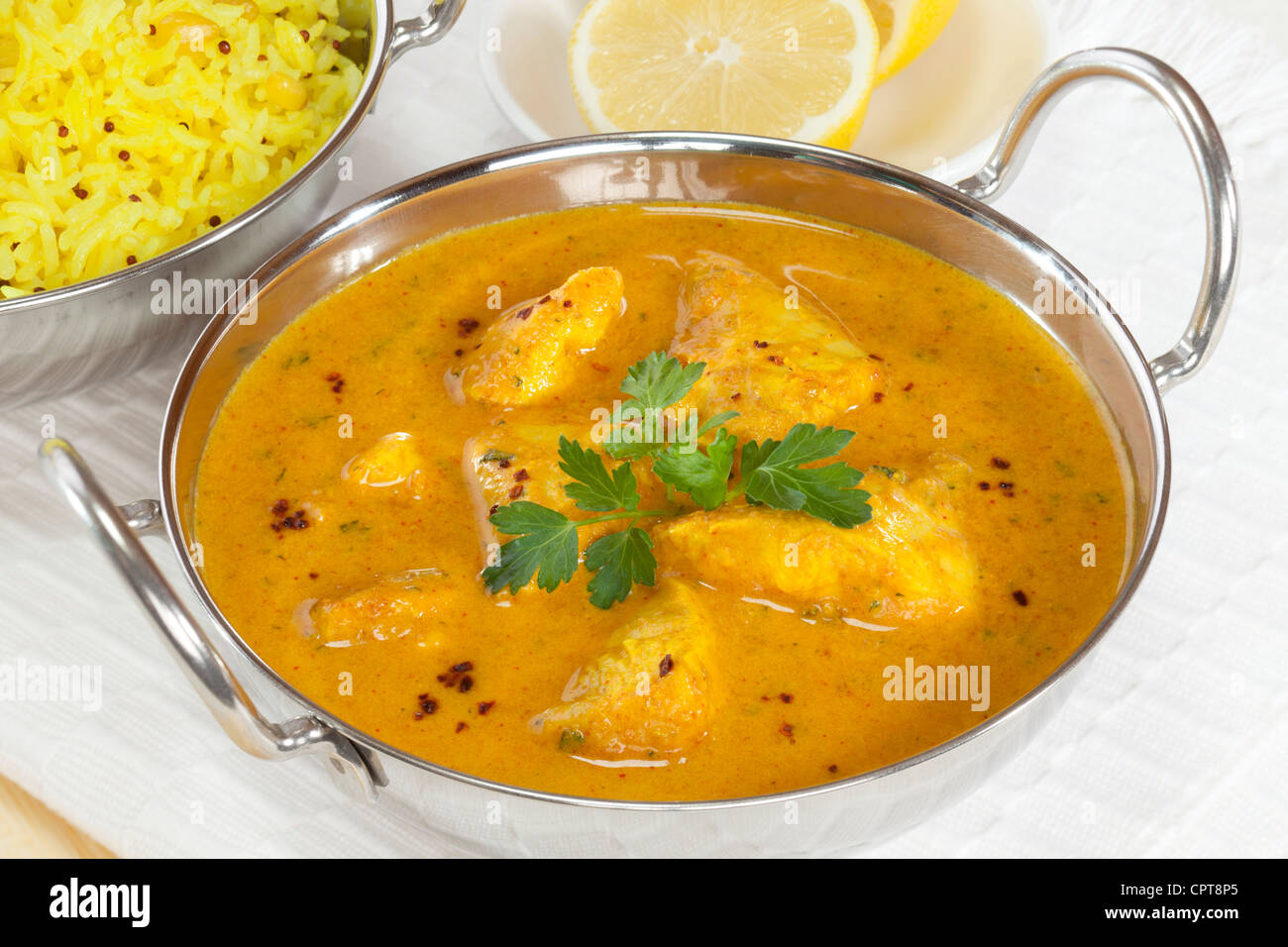 Balti un plat avec un style Peshwari poulet au curry, avec du riz basmati et du citron à l'arrière-plan. Banque D'Images