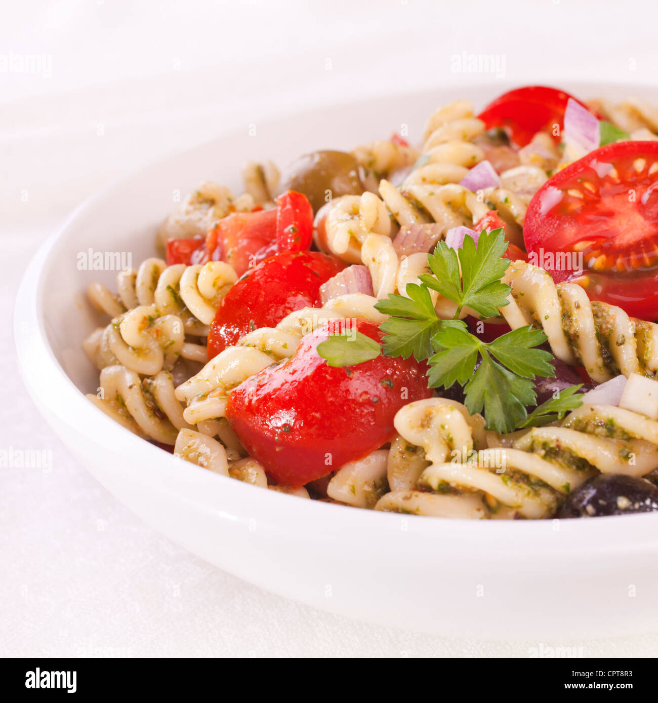 Salade de pâtes fusilli au pesto de roquette, juteux, tomates, olives et l'oignon. Banque D'Images