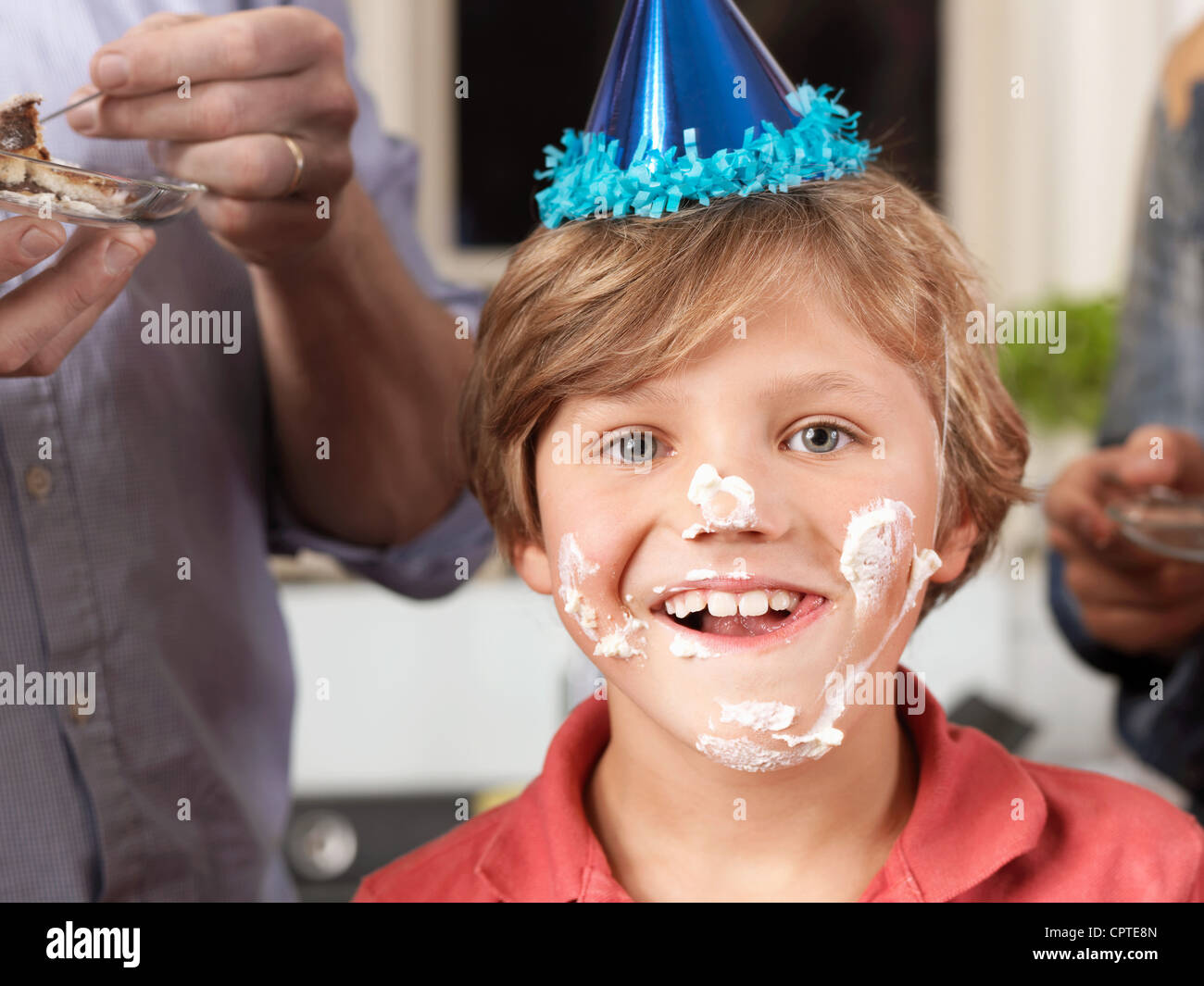 Portrait of boy in party hat avec gâteau enduit sur le visage Banque D'Images