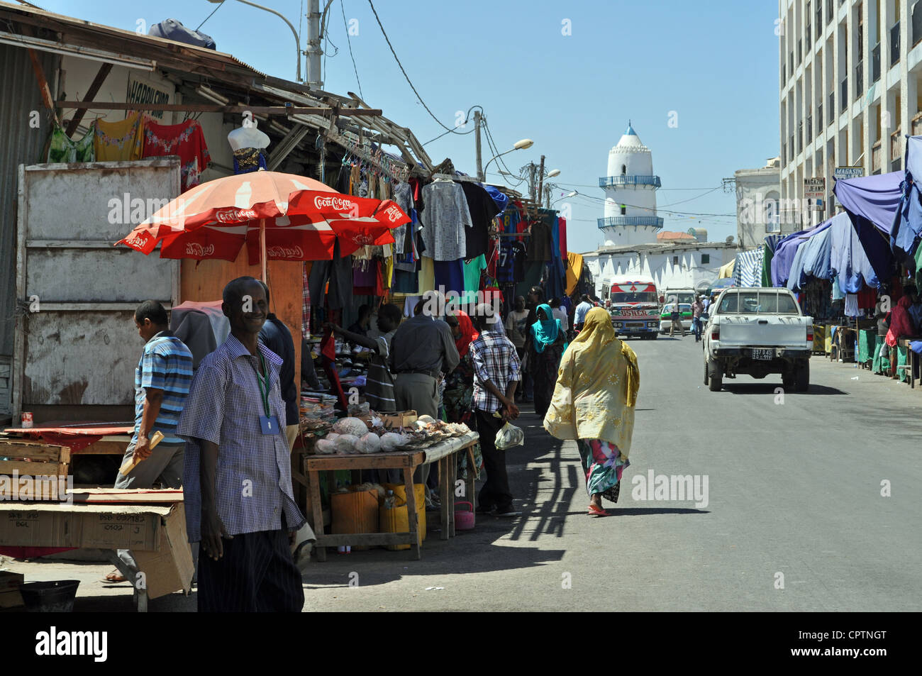 Une scène de rue dans la ville de Djibouti, avec des stands de marché à gauche et la mosquée historique de Hamoudi au bout de la route. Banque D'Images