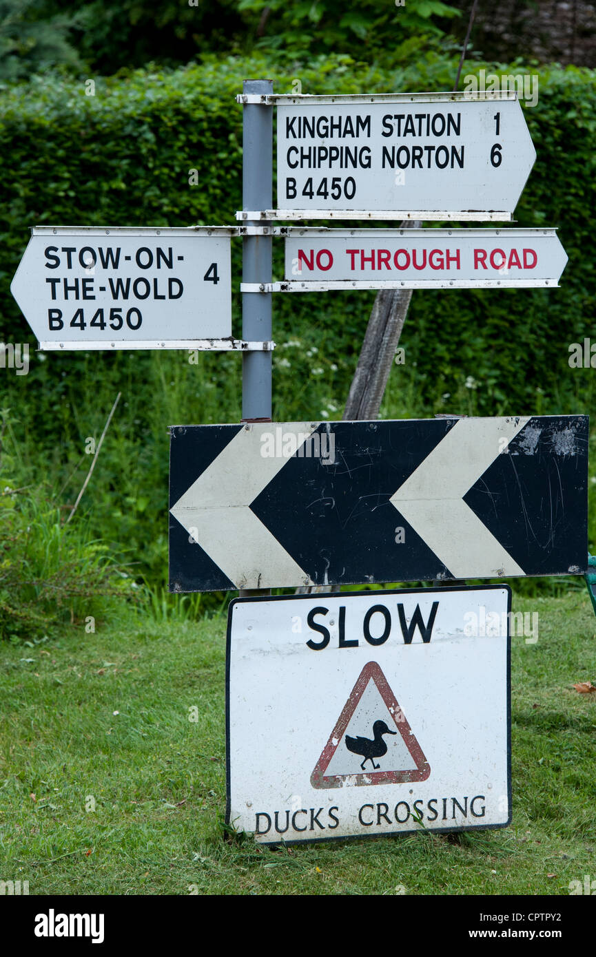Canards lente panneau de passage à niveau à côté d'un panneau routier. Kingham, Oxfordshire, Cotswolds , Angleterre Banque D'Images