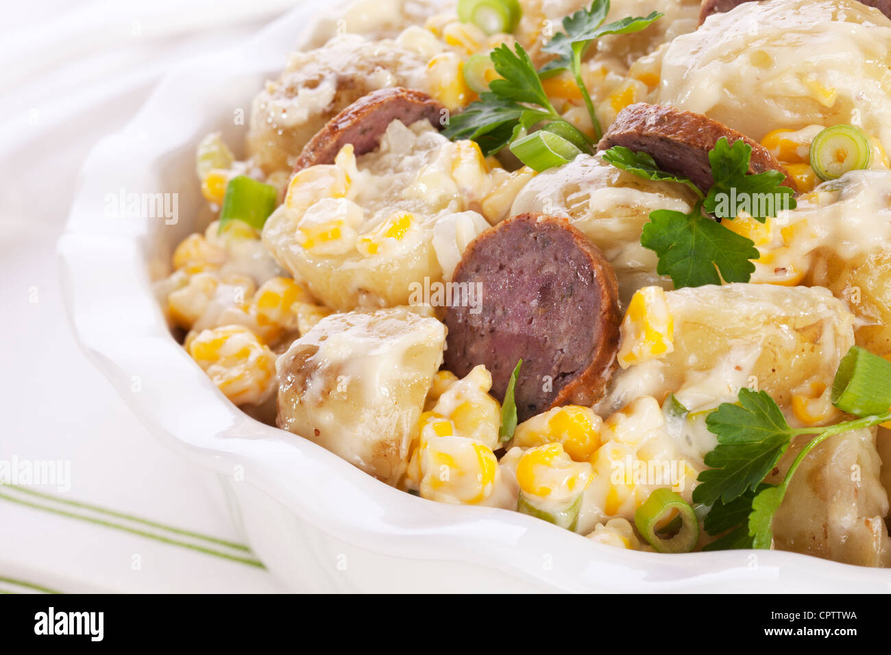 Salade de pommes de terre et de saucisses, de maïs doux et de l'oignon vert, garnie de persil, Close up. Banque D'Images