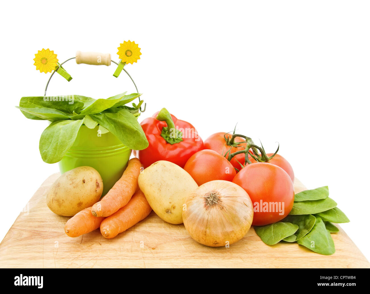 Des légumes frais du jardin - épinards, tomates, pommes de terre, carottes et poivrons rouges, sur une planche à découper en bois. Banque D'Images