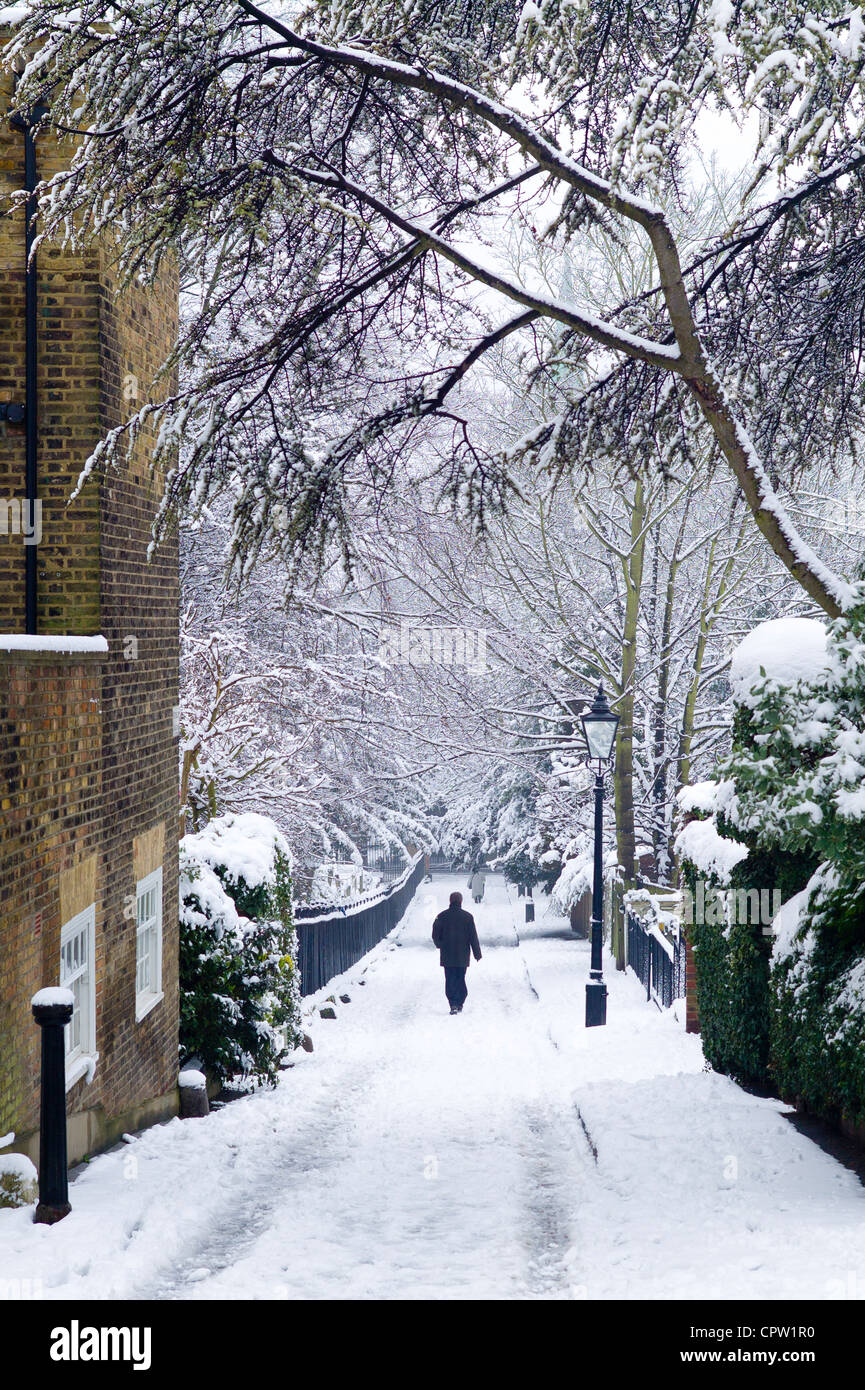 La figure solitaire de promenades à travers la neige profonde dans la région de Holly Place dans le quartier verdoyant de Hampstead, au nord de Londres, Royaume-Uni Banque D'Images