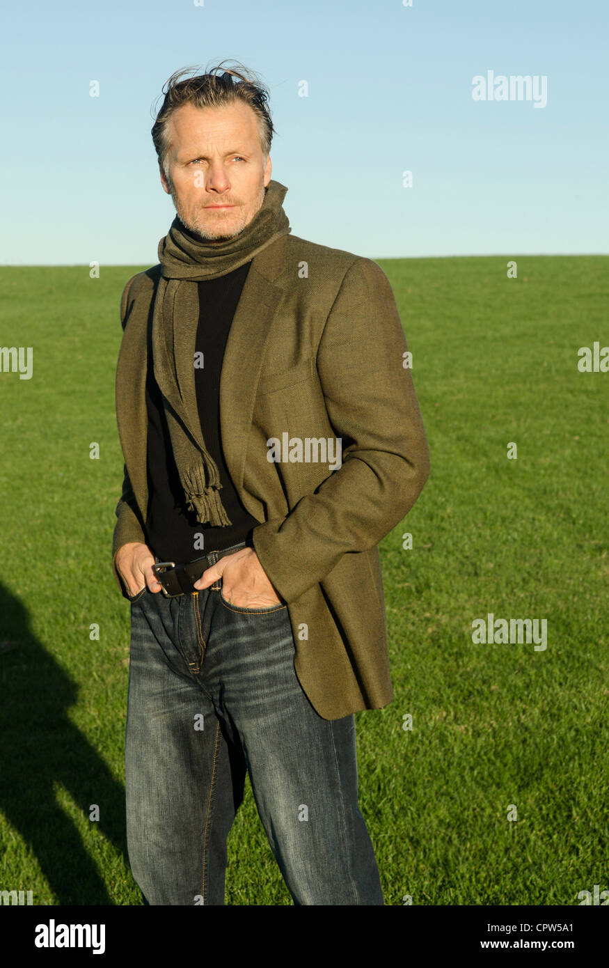 Un portrait d'un bel homme mûr d'une quarantaine d'debout dans un champ portant un foulard vert et veste. Banque D'Images
