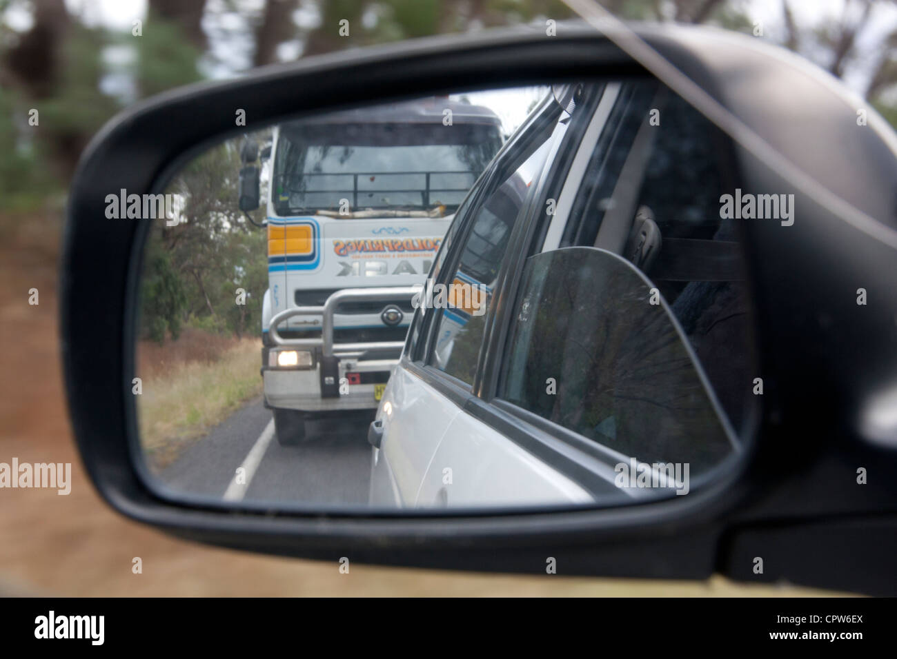 Voir rétroviseur de voiture avec la conduite de camions dangereusement derrière New South Wales Australie Banque D'Images