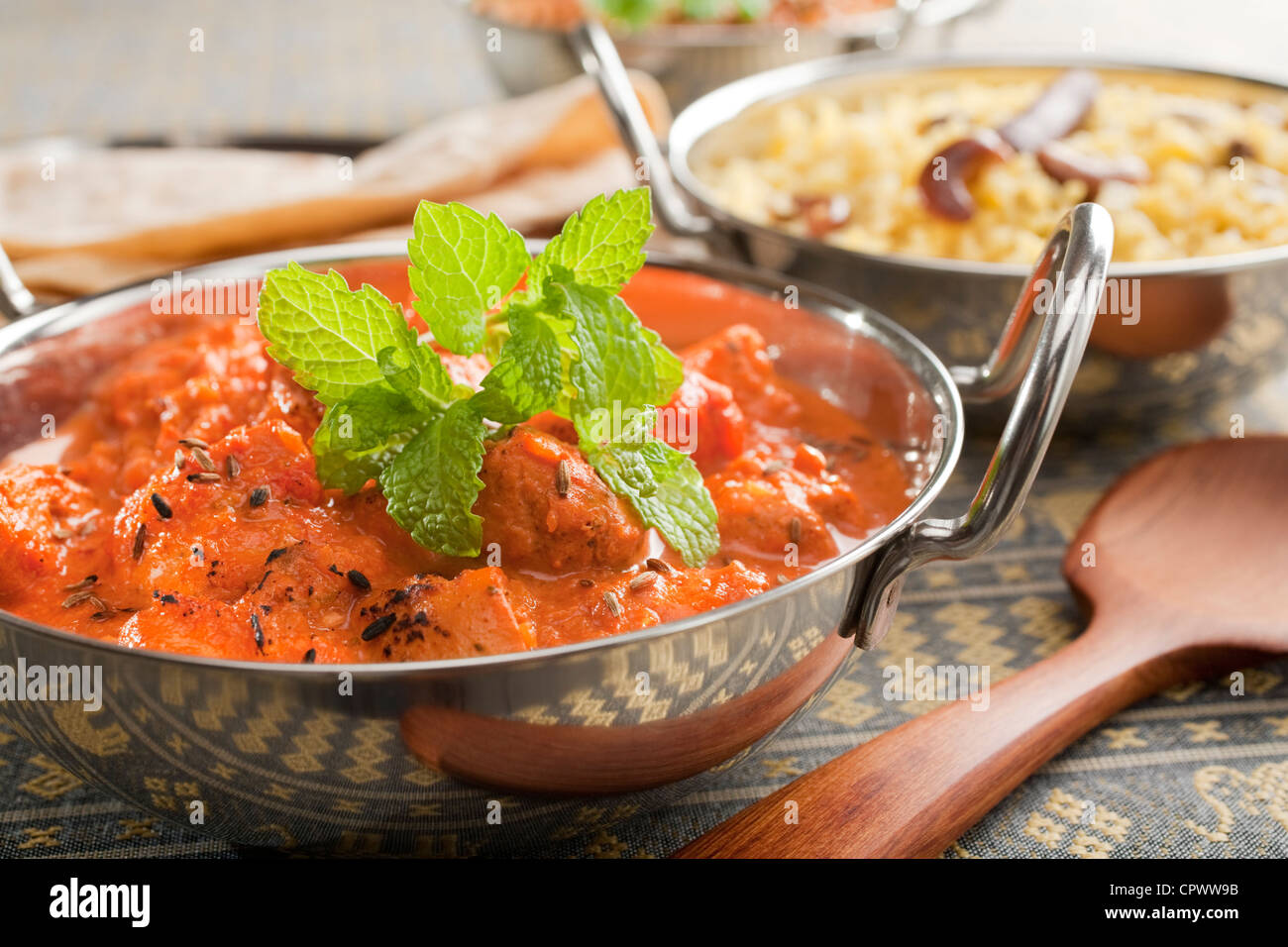 Repas indien de poulet tikka masala, garni de menthe, dans un plat ou balti karahi, accompagné de riz pilaf et chapati. Banque D'Images