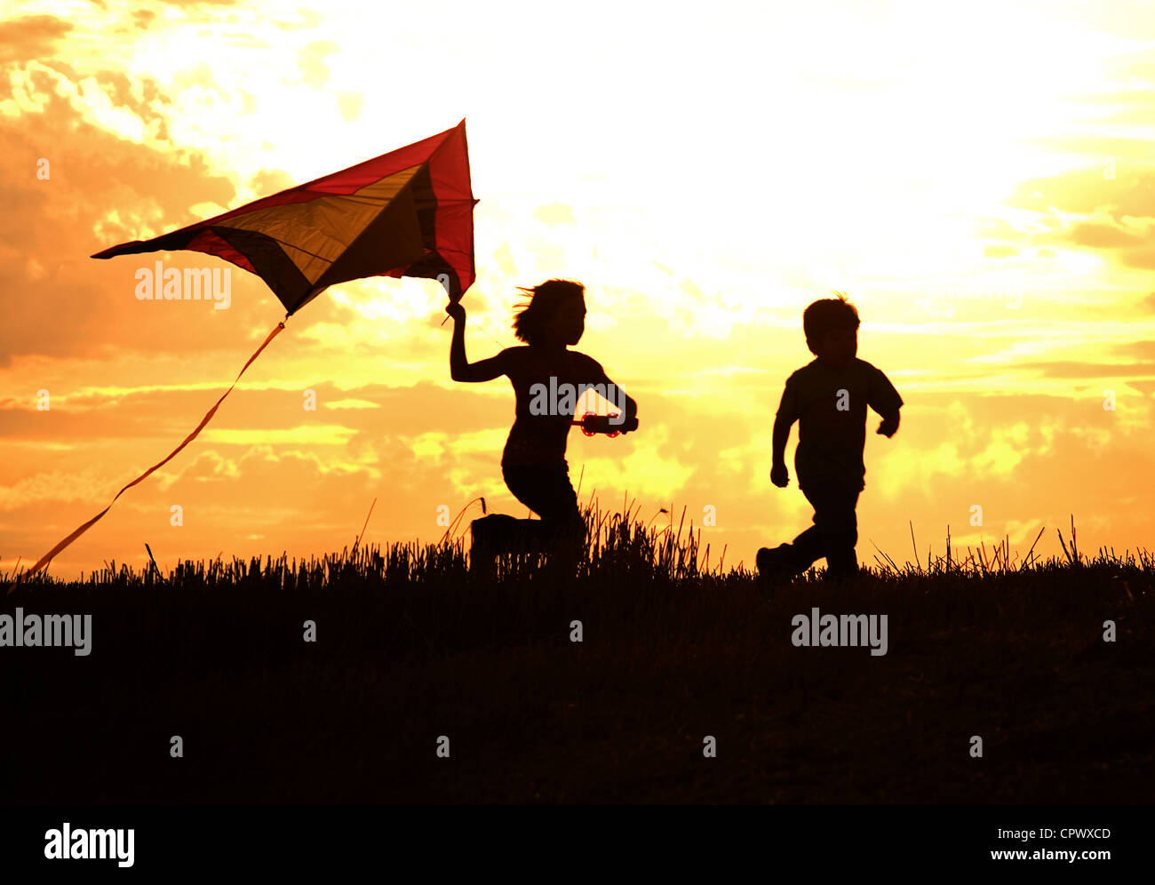Deux enfants voler un cerf-volant au coucher du soleil invoquer les souvenirs d'enfance. Banque D'Images