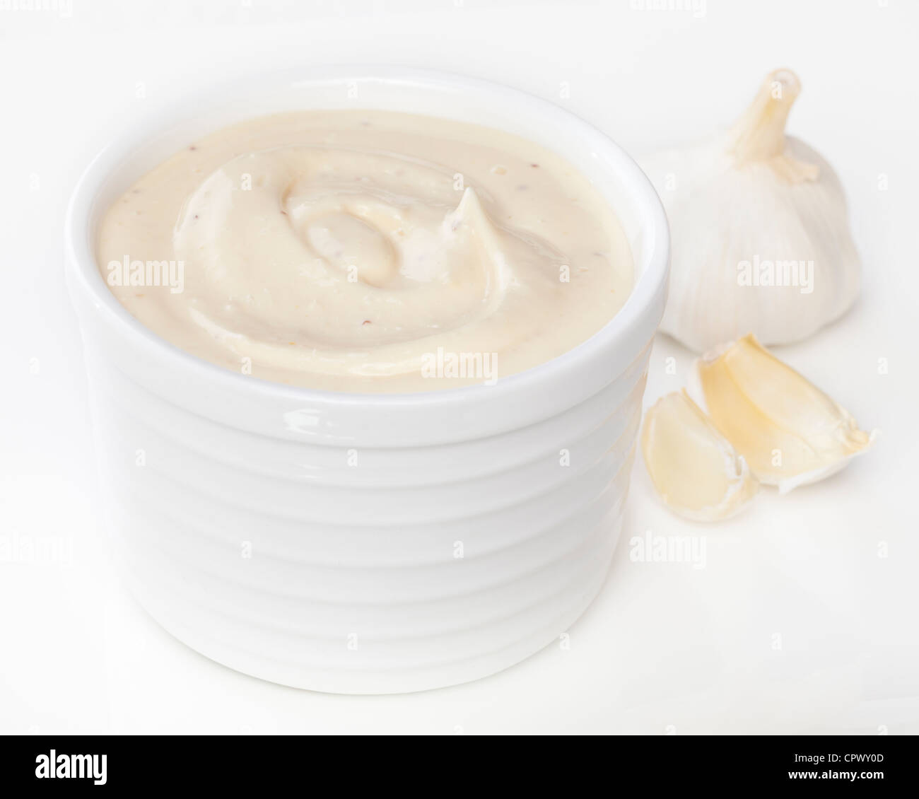 Un pot de mayonnaise à l'ail, aïoli, avec l'ail frais en arrière-plan. Banque D'Images