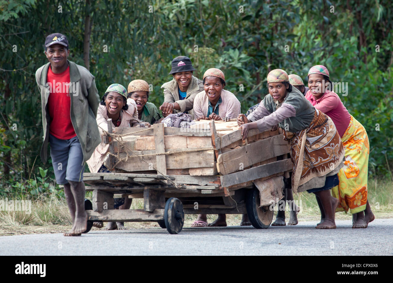 Un homme tirant et poussant sept femmes panier de briques en amont, près de Ranomafana, le centre de Madagascar. Banque D'Images