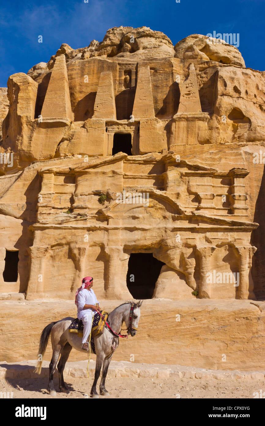Man riding sur le cheval avec le tombeau d'obélisques, Petra, Jordanie (site du patrimoine mondial de l'UNESCO) Banque D'Images