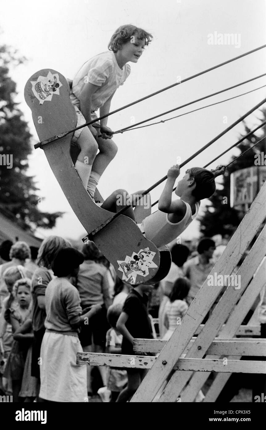 Les enfants jouissent de la swingboat ride à Ditchling Village juste en 1984 Sussex Banque D'Images