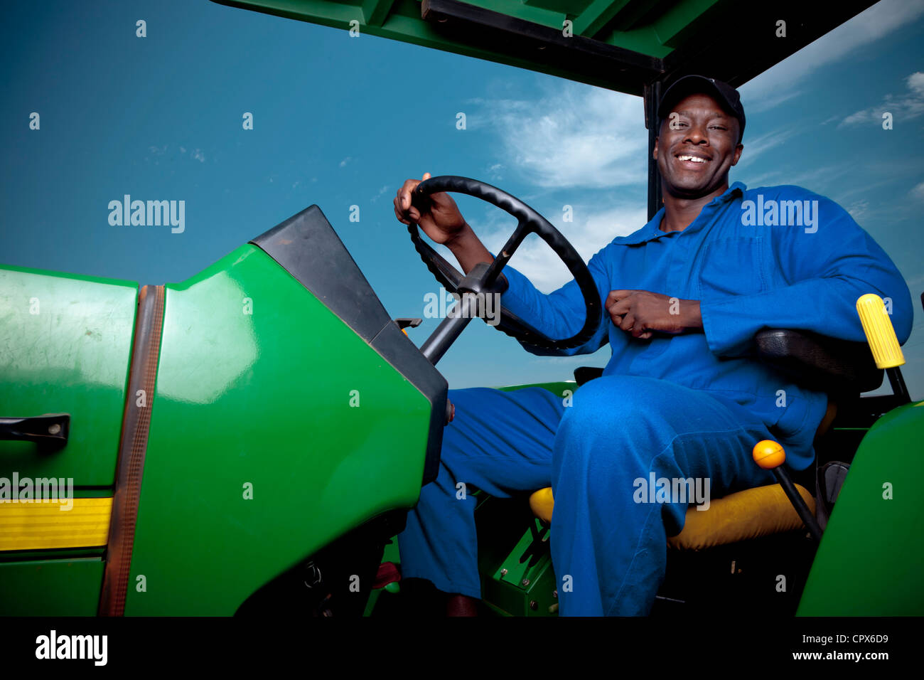 Travailleur agricole noir conduire un tracteur, smiling Banque D'Images