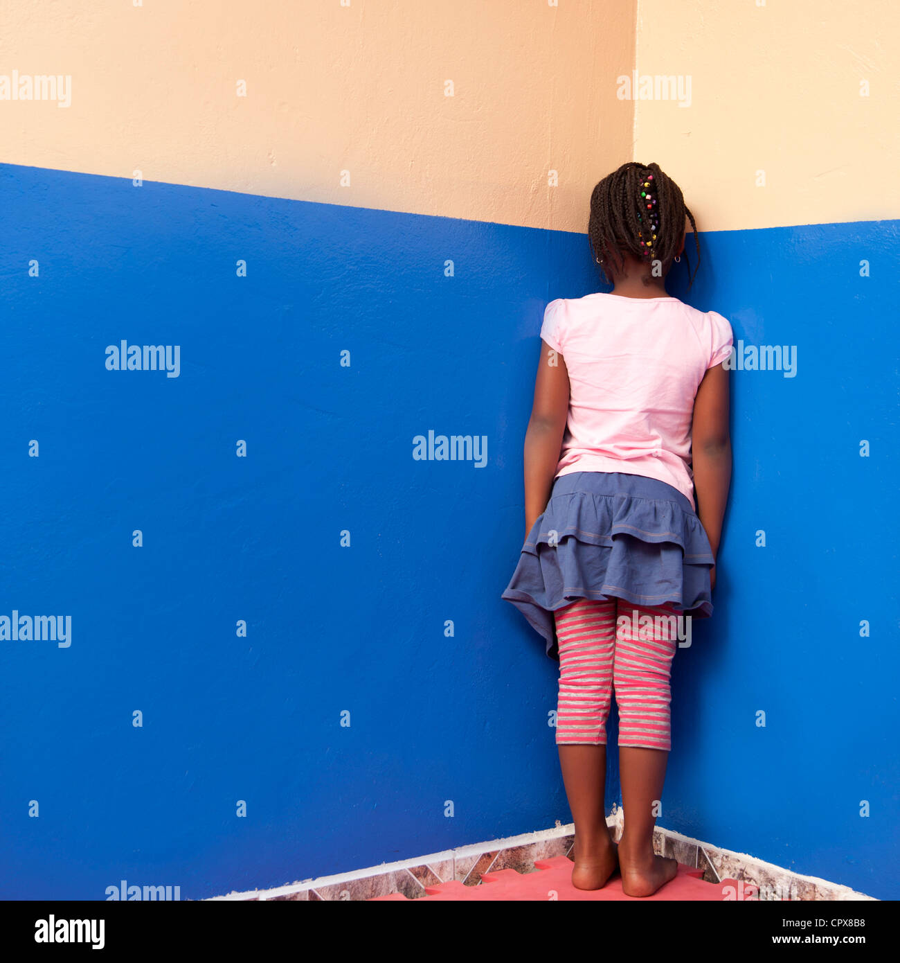 Enfant debout dans l'angle, face au mur Banque D'Images