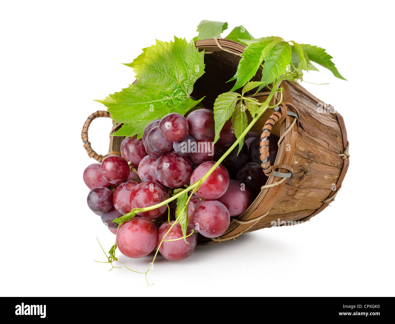 Raisin bleu foncé dans un panier en bois isolé sur fond blanc Banque D'Images