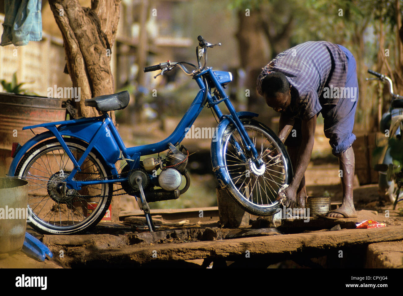 Mali, Mopti, l'homme à la recherche après son cyclomoteur, un moyen de transport très utilisé Banque D'Images