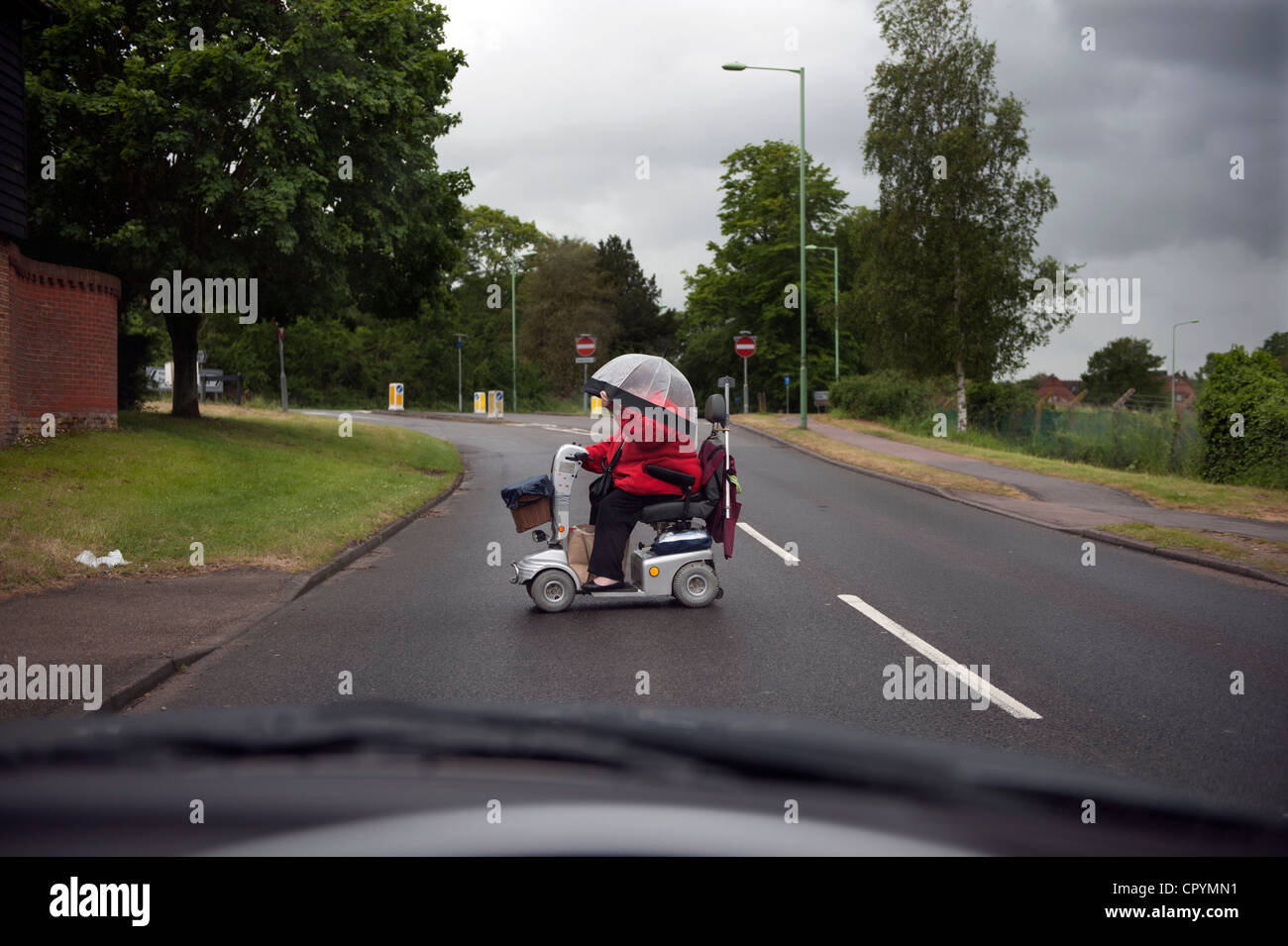 Handicap Scooter, Bungay, Suffolk, Angleterre, Royaume-Uni. Juin 2012. Femme pilote sur un scooter pour personnes handicapées, traverse la route. Banque D'Images