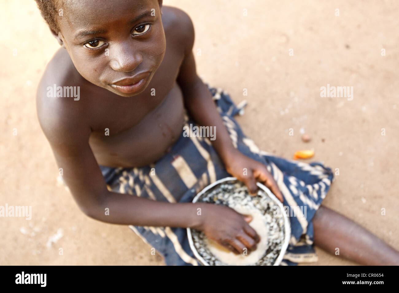 Un enfant mange un repas de foufou (pilonnèrent yam) et sauce aux légumes dans le village d'Djorbana, région du Zanzan, Côte d'Ivoire Banque D'Images