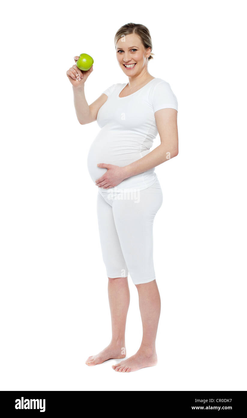 Femme enceinte montrant apple vert frais tout en tenant son ventre. Plus isolé sur fond blanc Banque D'Images