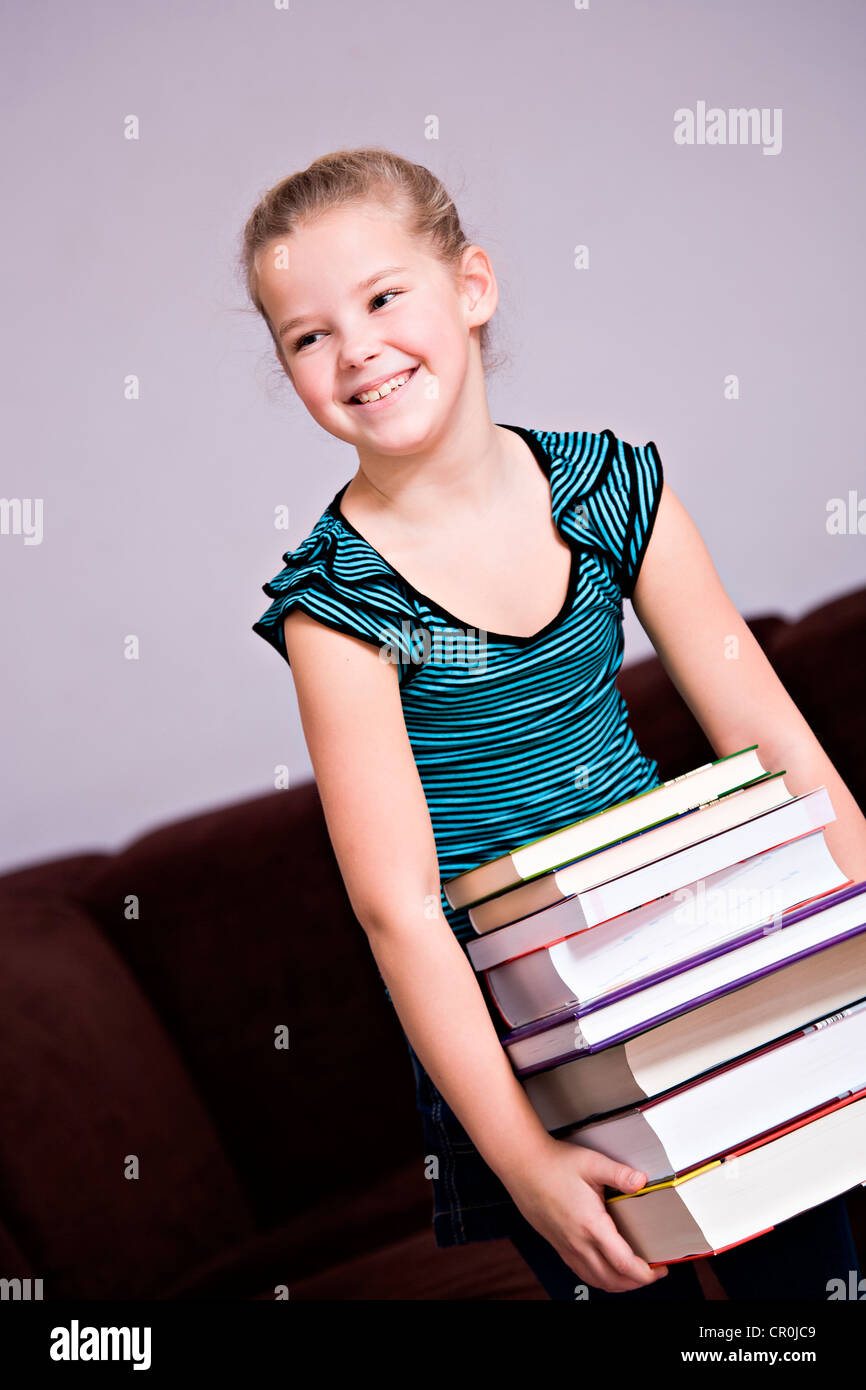 Fille, 8, portant une pile de livres Banque D'Images