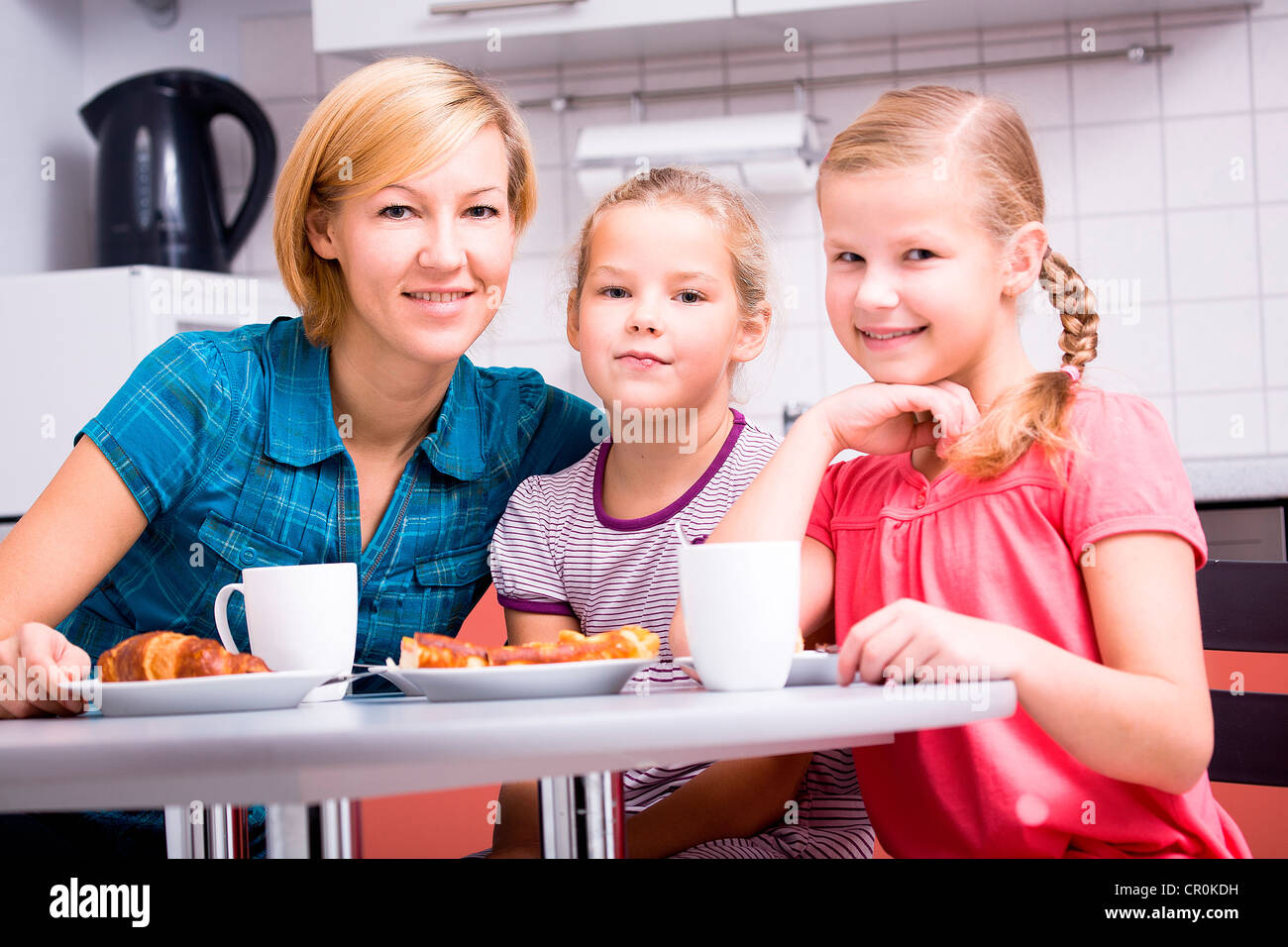 La mère et les deux filles de prendre le petit déjeuner dans la cuisine Banque D'Images