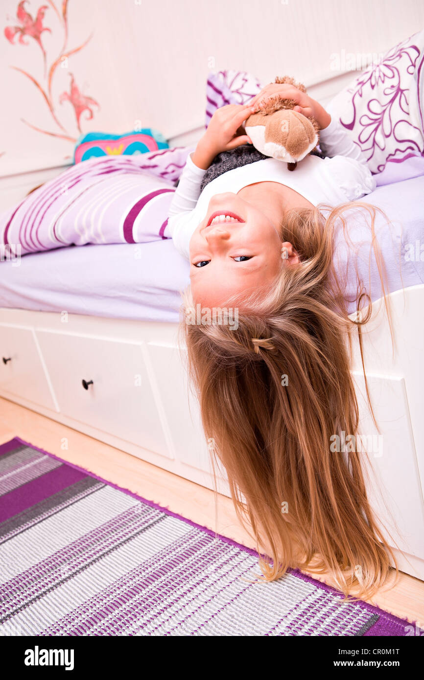 Fille, 9, couché avec un animal en peluche sur son lit Banque D'Images