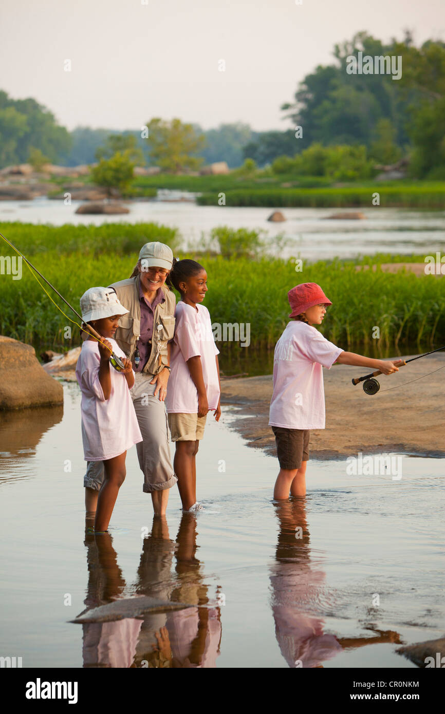 Femme enseigner aux enfants comment voler des poissons sur la rivière Banque D'Images