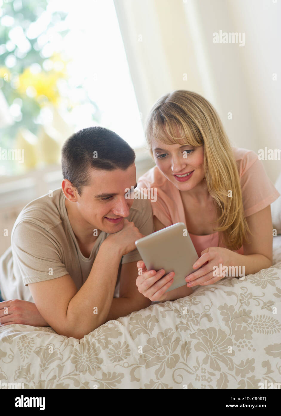 USA, New Jersey, Jersey City, Couple lying on bed and using digital tablet Banque D'Images