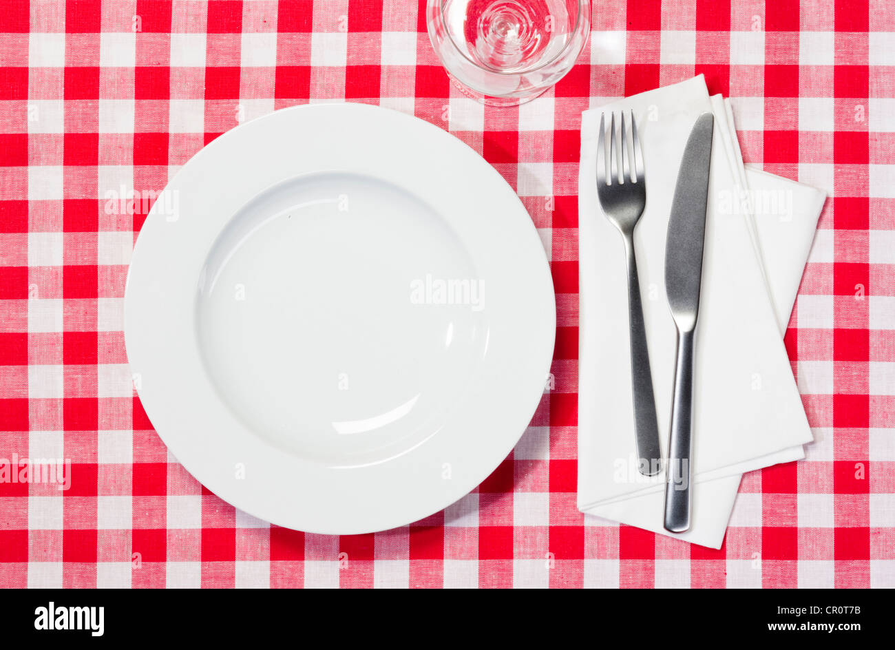Set table avec une assiette, un verre, un couteau et une fourchette sur une  nappe à carreaux rouges et blancs Photo Stock - Alamy