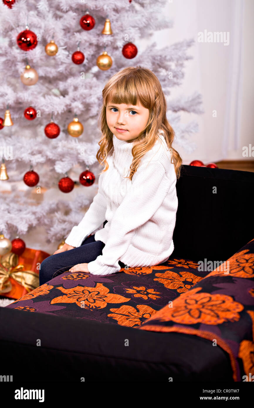 Jeune fille en face d'un arbre de Noël dans un salon Banque D'Images