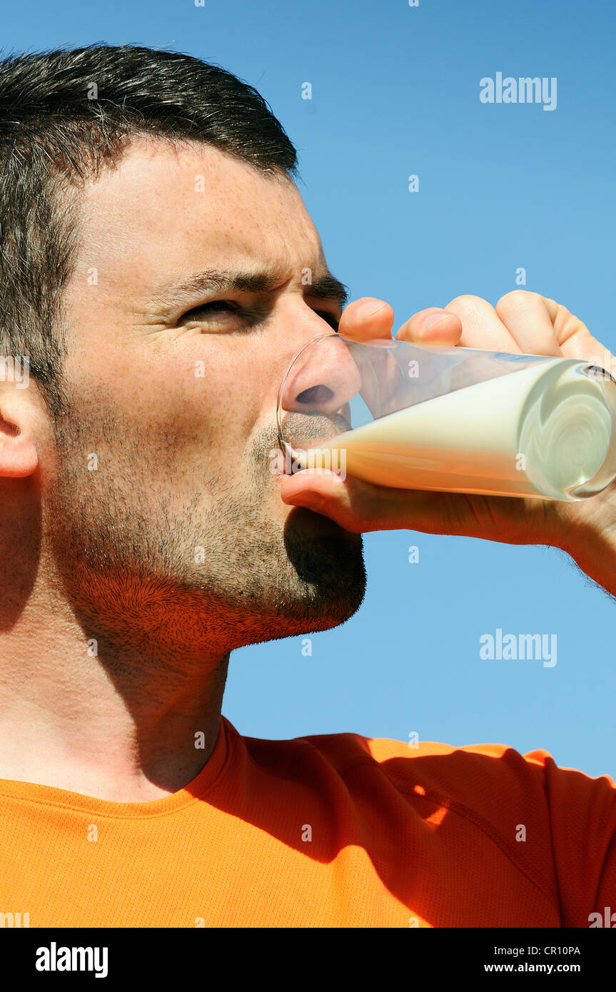 L'homme est de boire un verre de lait frais dans les blue skye Banque D'Images