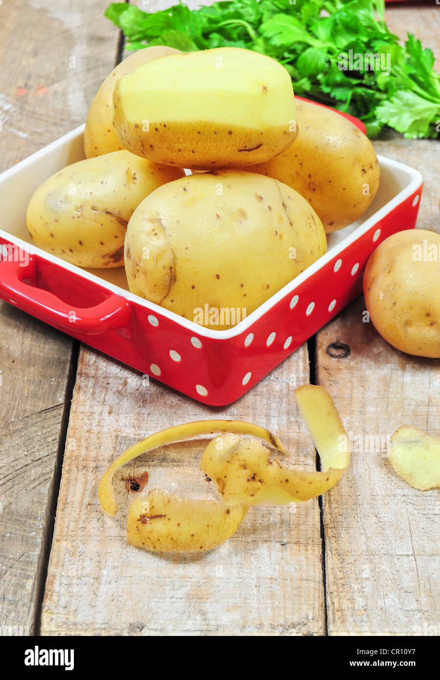 Les pommes de terre crues dans le bac rouge et de pelures de pommes de terre Banque D'Images