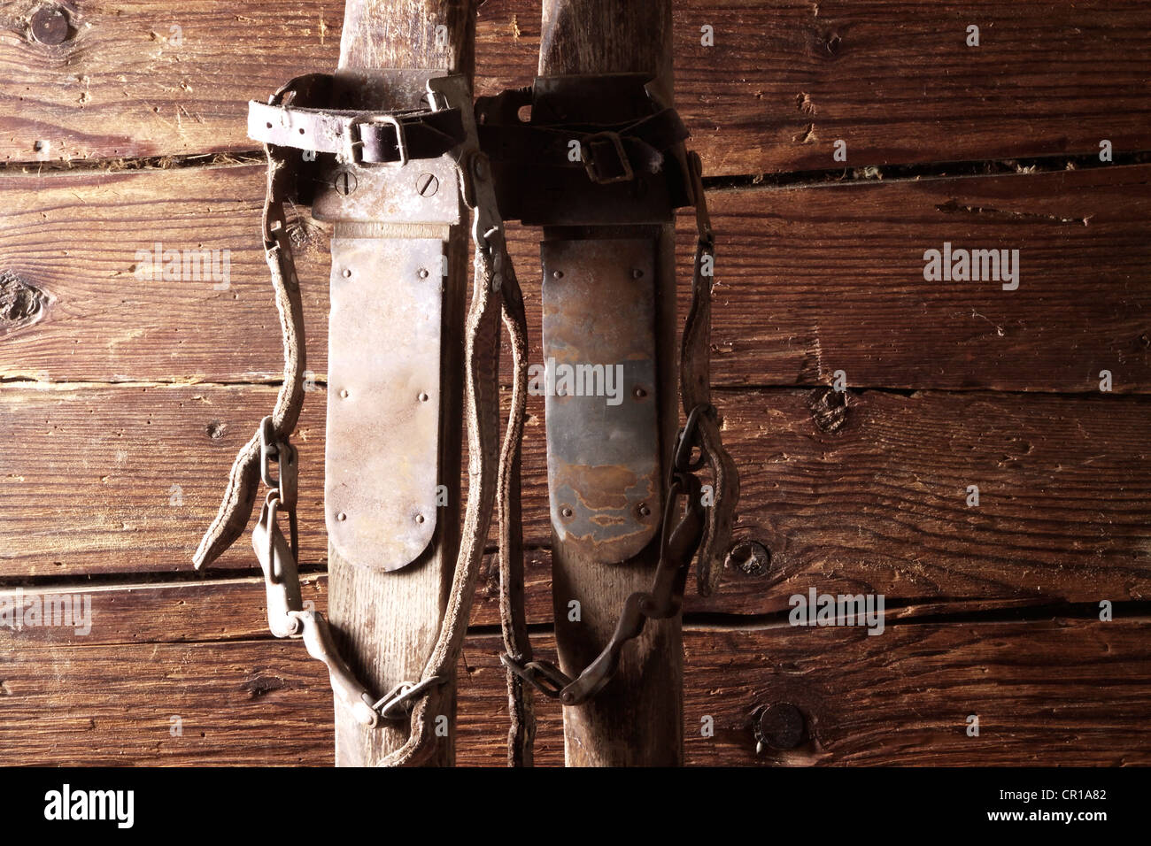Vieux skis en bois avec une lanière binding leaning on a rustic wooden wall Banque D'Images