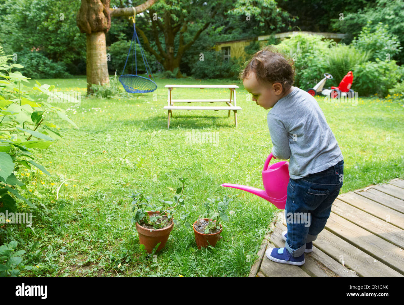 Bébé garçon watering plants in backyard Banque D'Images