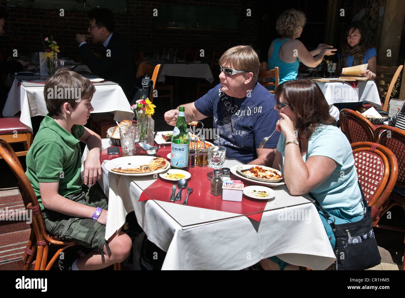 Famille avec tween fils assis à table à l'extérieur du trottoir restaurant italien sur Mulberry street eating Pizza & Pasta New York City Banque D'Images