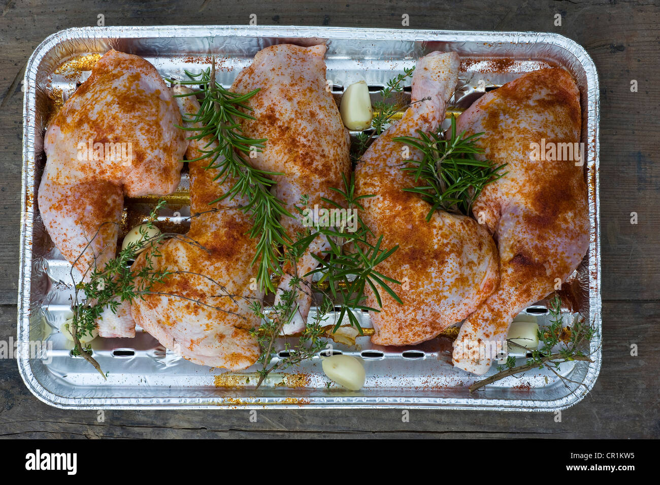Haut de cuisses de poulet assaisonné de romarin, thym et l'ail dans une casserole en aluminium prêt pour la cuisson au barbecue Banque D'Images