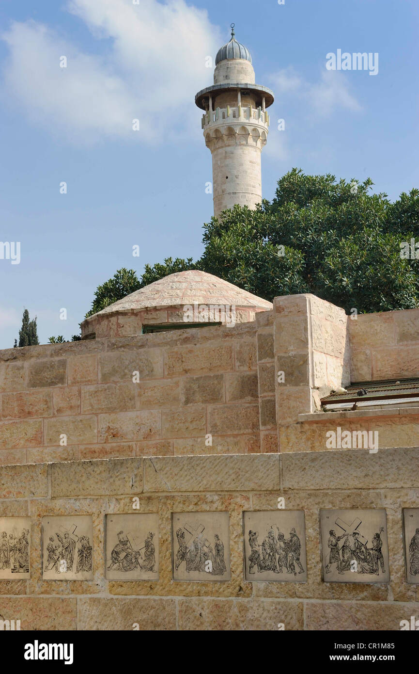 Monument chrétien sur la Via Dolorosa, reliefs de la Passion de Jésus, dans le quartier arabe, en face d'un minaret sur le mont du Temple Banque D'Images